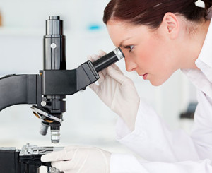 female researching looking through a microsope.