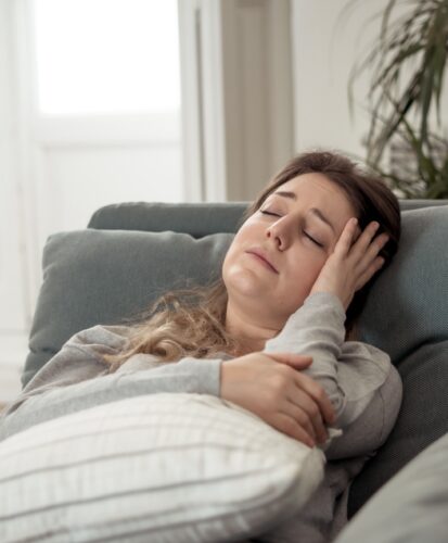 Fatigued woman on couch suffering from insulin resistance, needing a Rosemark obgyn doctor.