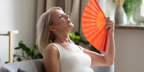 Woman fanning herself while having a hot flash. Obgyn doctors in Idaho Falls are conducting a clinical research study.