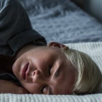 Woman in pain, laying on her bed. Click to learn more about our Eximis hysterectomy clinical study.